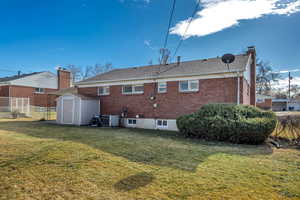 Rear view of house featuring a shed, brick siding, and a chimney