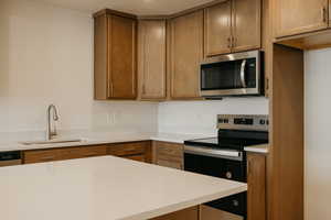 Kitchen featuring stainless steel appliances, wood finish cabinetry, and light stone counters
