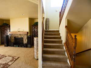Stairs featuring a stone fireplace and carpet floors