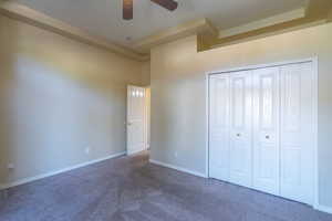 Unfurnished bedroom with dark carpet, a ceiling fan, a closet, and a high ceiling