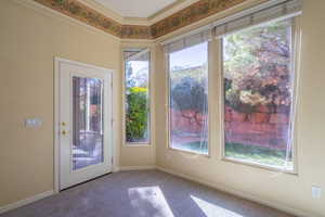 Doorway to outside featuring crown molding and carpet