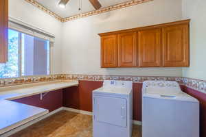 Laundry area with washer and dryer, ceiling fan, cabinet space, and a wainscoted wall