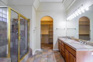 Full bath with a walk in closet, double vanity, and a shower stall