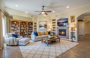 Virtually Staged Living area with built in features, arched walkways, a ceiling fan, a fireplace, and light tile patterned floors
