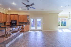 Kitchen with wood finish cabinets, a ceiling fan, healthy amount of natural light, a kitchen breakfast bar, and a textured ceiling