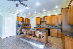 Kitchen with stainless steel refrigerator with ice dispenser, a kitchen breakfast bar, glass fronted cabinets, a kitchen island, and dishwasher