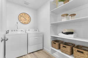 Laundry area featuring light wood-style floors and washing machine and dryer