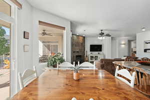 Dining area with a tile fireplace and a ceiling fan
