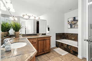 Full bath with double vanity, a bath, and light tile patterned floors