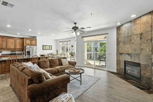 Living room with a fireplace, recessed lighting, a ceiling fan, and light wood-style floors
