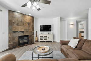 Living area featuring ceiling fan, a tiled fireplace, wood finished floors, and recessed lighting