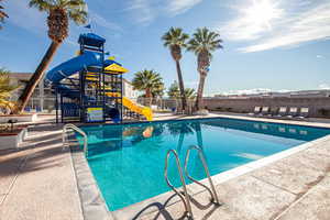 Community pool with a water slide and a patio