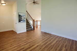 Unfurnished living room featuring a high ceiling, wood finished floors, and ceiling fan