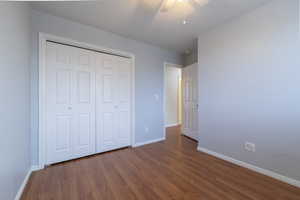 Unfurnished bedroom with dark wood-style floors, a ceiling fan, and a closet