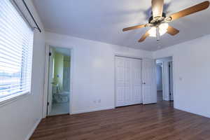 Unfurnished bedroom with dark wood finished floors, ceiling fan, connected bathroom, and a closet