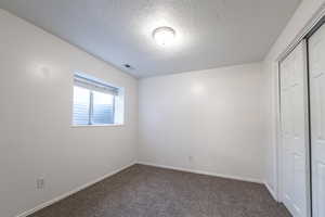 Unfurnished bedroom with a textured ceiling, a closet, and carpet