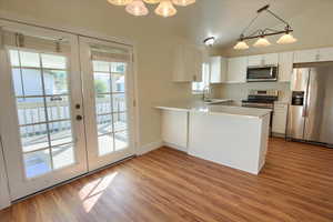 Kitchen featuring stainless steel appliances, light countertops, white cabinetry, a chandelier, and french doors