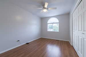 Unfurnished bedroom featuring a closet, wood finished floors, and a ceiling fan