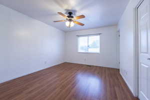 Spare room featuring dark wood-type flooring and ceiling fan