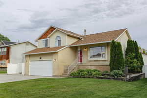Tri-level home featuring driveway, a garage, a shingled roof, and brick siding