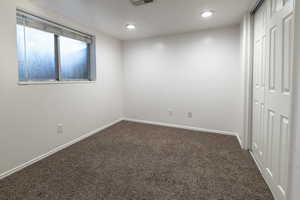 Unfurnished bedroom featuring a closet, dark carpet, and recessed lighting