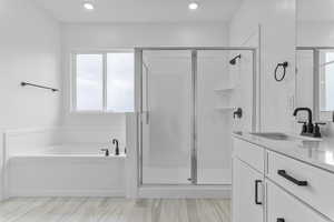 Bathroom with a stall shower, a bath, vanity, and recessed lighting