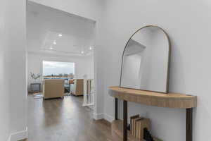 Hall featuring recessed lighting, wood-type flooring, and a tray ceiling