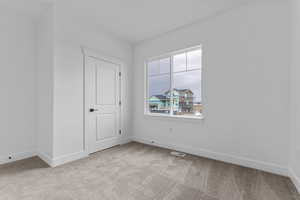 Unfurnished room featuring baseboards and light carpet