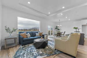 Living area with light wood-style floors, recessed lighting, and a tray ceiling