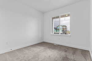 Spare room featuring carpet and baseboards