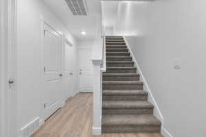 Stairway with wood finished floors and recessed lighting