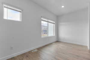 Empty room with light wood-type flooring and recessed lighting