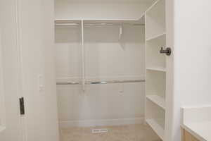 Walk in closet with light colored carpet