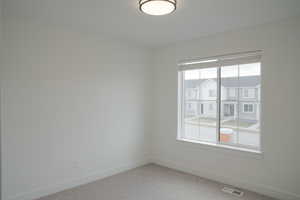 Empty room featuring light colored carpet and baseboards