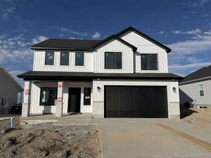 Modern farmhouse featuring a porch, an attached garage, concrete driveway, and board and batten siding