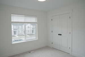 Unfurnished bedroom with a closet and light colored carpet