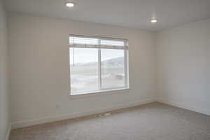Empty room with light colored carpet, recessed lighting, and a mountain view