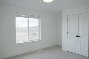 Unfurnished bedroom with light colored carpet and a closet
