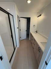 Bathroom featuring double vanity, light wood-type flooring, and a stall shower