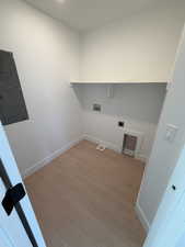 Laundry room featuring light wood-type flooring, electric panel, hookup for a washing machine, and hookup for an electric dryer