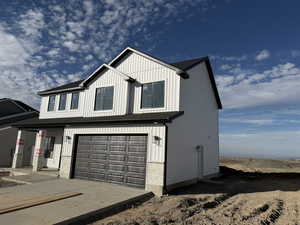 View of front of property with a garage, board and batten siding, concrete driveway, and covered porch