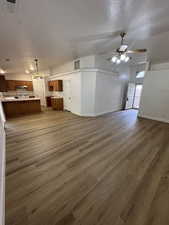 Unfurnished living room with a textured ceiling, dark wood-style floors, and ceiling fan