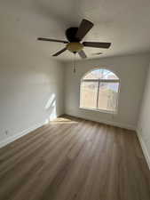 Unfurnished room featuring light wood-style floors, a textured ceiling, and a ceiling fan