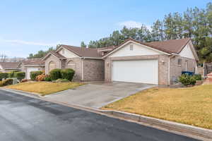 Ranch-style house with a tiled roof, driveway, a garage, a front yard, and brick siding