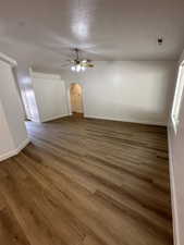 Empty room with arched walkways, ceiling fan, a textured ceiling, and wood finished floors