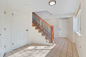 Entryway with stairway and light tile patterned floors