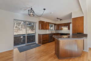 Kitchen with a peninsula, light wood flooring, granite counter tops, dishwasher, black / electric stove.
