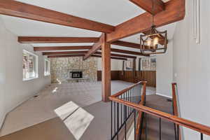 Unfurnished room featuring a woodburning stove, beam ceiling.