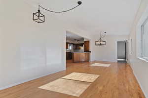 Unfurnished dining area featuring suspended lighting and light wood flooring