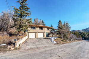 View of front of home featuring a garage, asphalt driveway, a balcony, and a mountain view